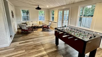 Relax in a spacious room with a sofa, chairs, and a foosball table.
