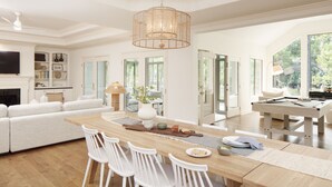 A spacious living room with a large wooden dining table, white chairs, a white sofa, and a pool table. - Hilton Head Retreat • Private Pool + Deck Dining + Near Beach | Hilton Lagoon (Hilton Head Island)