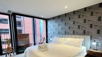 Un dormitorio moderno con una cama grande, un papel tapiz estampado y vistas al exterior.