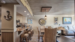 Una cocina moderna con una isla central, sillas de madera y una mesa de comedor.