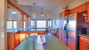 A spacious kitchen with wooden cabinets, a large island, and a stainless steel refrigerator. - Ultimate Private Desert Escape, Infinity Pool, Million-Dollar View (Tucson)