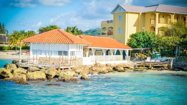 Un edificio sul lungomare con tetto in tegole rosse, facciata bianca e un balcone vista mare.
