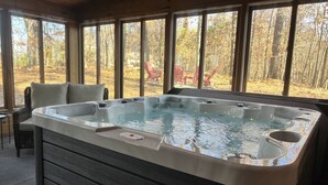 Un jacuzzi en una habitación con ventanas amplias que dan a un bosque.