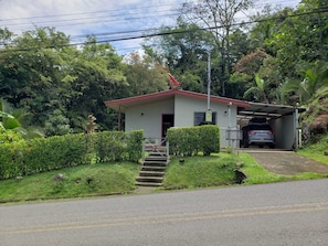A small building with a red roof, a covered parking area, and a staircase leading to the entrance. - Naturist's Paradise (Guadalajara Rio Piedras)
