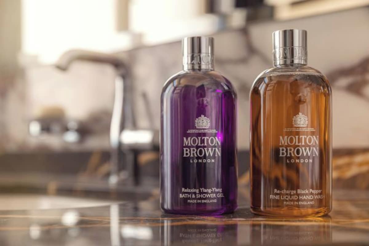 Två flaskor Molton Browns bad- och duschgel placerade på en reflekterande yta.