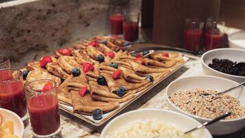 Un bufé de desayuno con gofres, bayas y diversas opciones para el desayuno.