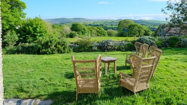 A grassy outdoor area with wicker furniture and a stone wall. - Henllys (Crymych)
