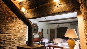 A rustic interior with exposed wooden beams, a stone wall, a fireplace, and a cozy seating area with a sofa and armchairs. - Henllys (Crymych)