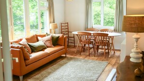 A cozy living room with a sofa, chairs, a table, and large windows. - Henllys Lodge (Crymych)