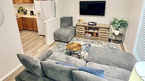 A living room with a grey sofa, a coffee table, and a TV mounted on the wall.
