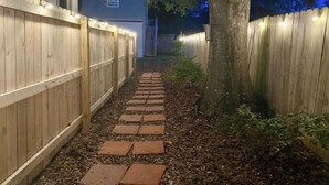 A narrow pathway leading to a house with a wooden fence on both sides.