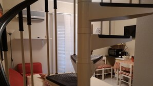 A staircase leading to a room with a desk, a chair, a small table, and a window with blinds. - Private apartment (Chianchitta)