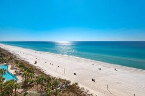 A beach with a pool, palm trees, and a clear sky. - Welcome to 707 West!  GULFFRONT with Free Beach Service and Activities! (Panama City Beach)