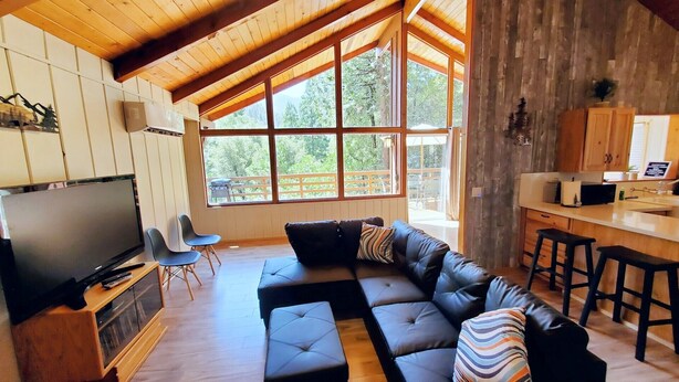 A spacious living room with a large sectional sofa, a flat-screen TV, and a wooden ceiling.