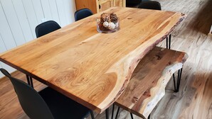 A wooden dining table with a unique curved design, accompanied by black chairs.