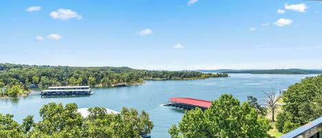 A lakeside view with a dock, a red-roofed structure, and lush greenery.