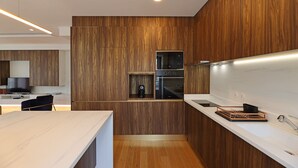 A modern kitchen with wooden paneling, a built-in oven, and a stainless steel sink.