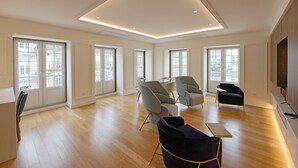 A spacious living room with large windows, modern furniture, and a recessed ceiling light.