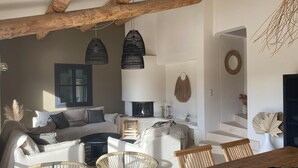 A cozy living room with a fireplace, wooden beams, and a dining area with a table and chairs. - Maison ELA à lourmarin (Lourmarin)