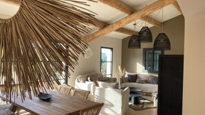 A spacious living area with a wooden dining table, a sofa set, and a large window providing natural light. - Maison ELA à lourmarin (Lourmarin)