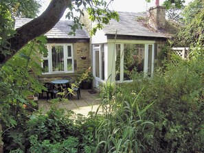 Ein Steinhaus mit Terrasse, überdachter Sitzgelegenheit und Garten.