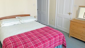 Un dormitorio con cama, cómoda y dos puertas.