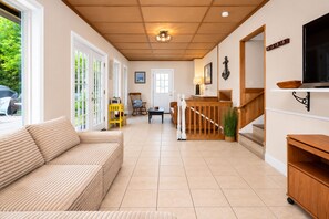 A spacious living area with a sofa, a dining table, and a staircase leading to a loft.