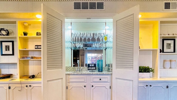 A kitchen with white cabinetry, a wine rack, and a coffee machine.