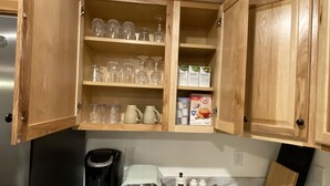A kitchen with wooden cabinets, a coffee maker, a kettle, and a tray with salt, pepper, and sugar containers.