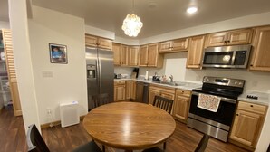 A modern kitchen with wooden cabinets, stainless steel appliances, and a round dining table.
