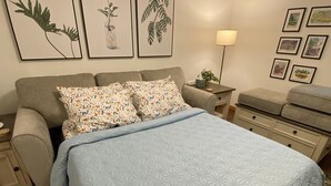 A bedroom with a bed, a nightstand, a dresser, and a lamp.