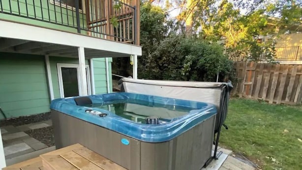 A hot tub with a cover, a wooden bench, and a patio area.