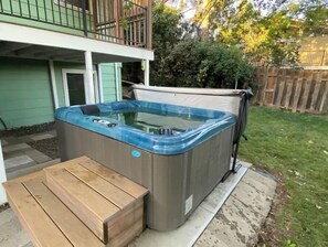 Een hottub met een deksel, een houten bankje en een terras.