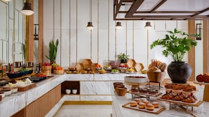 A modern kitchen with marble countertops, wooden accents, and a variety of food items displayed. - The Ritz-Carlton, Baku (Baku)