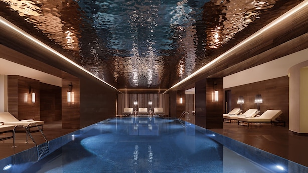 An indoor swimming pool with a modern design, featuring a central seating area with lounge chairs and a reflective ceiling. - The Ritz-Carlton, Baku (Baku)