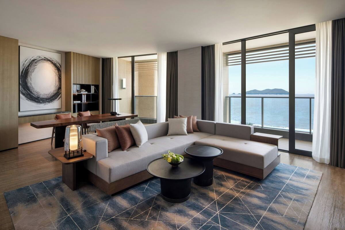 Ein modernes Wohnzimmer mit einer großen Eckcouch, einem Couchtisch und einem Essbereich mit einem hohen Tisch und Stühlen.