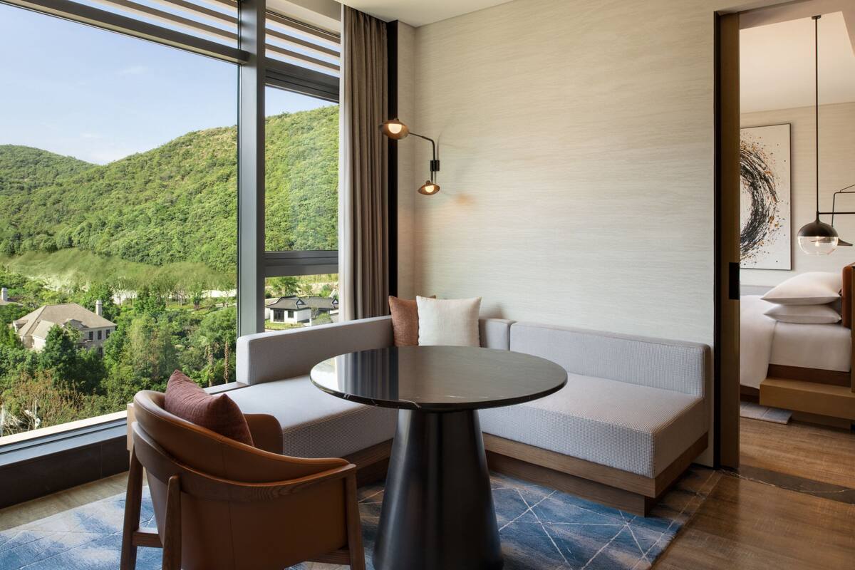 Ein modernes Hotelzimmer mit einem großen Fenster und Blick auf eine gebirgige Landschaft.