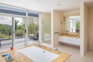 A modern bathroom with a large bathtub, a glass-enclosed shower, and a vanity with a mirror.