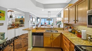 Una cocina moderna con encimeras de granito, electrodomésticos de acero inoxidable y armarios de madera.