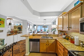 Una cocina moderna con encimeras de granito, electrodomésticos de acero inoxidable y armarios de madera.