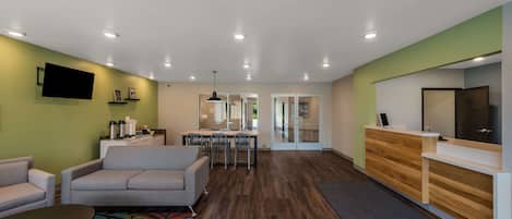 A modern hotel lobby with a reception desk, seating area, and a dining space.