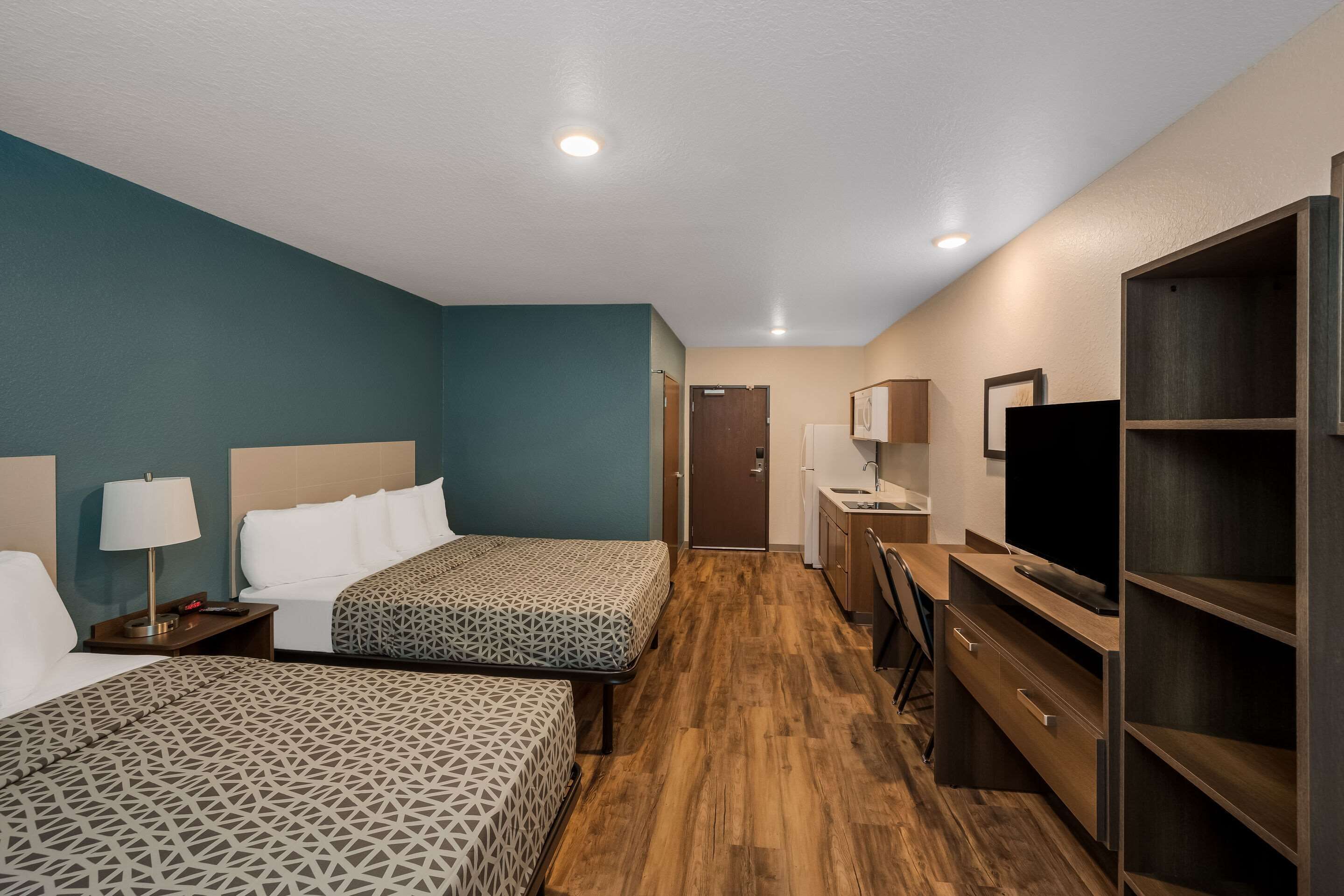 Habitación de hotel con dos camas, un escritorio, un televisor y un armario.