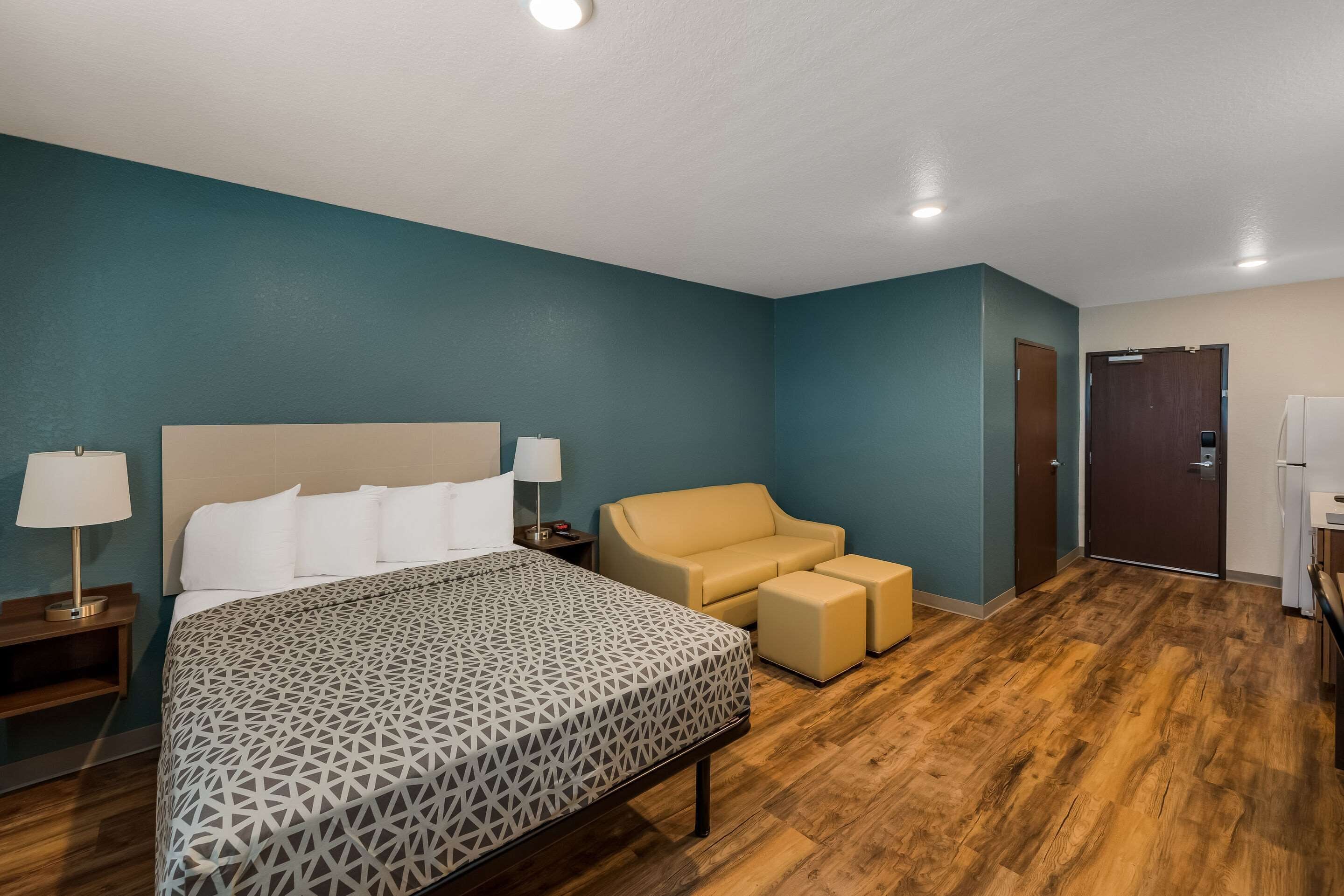 Quarto de hotel com uma cama grande, um sofá e uma pequena mesa com abajur.