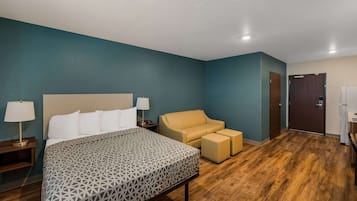 Quarto de hotel com uma cama grande, um sofá e uma pequena mesa com abajur.