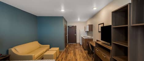 Una habitación de hotel con cama, sofá, escritorio, televisión y armario.