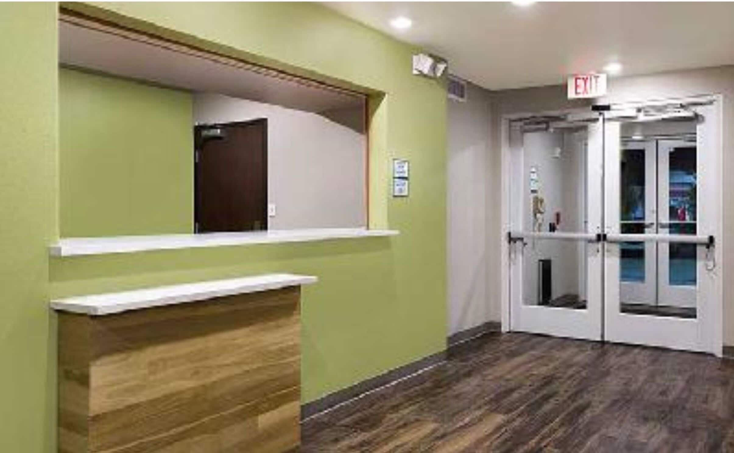 A reception area with a wooden counter, green walls, and a double door with glass panels.