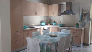 A compact kitchen with a dining area, featuring light wooden cabinets, a stainless steel range hood, and a small table with chairs. - Family retreat with private pool, be with your loved ones and create memories.... (São Bartolomeu de Messines)