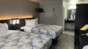 A hotel room with two beds, a nightstand, a wall-mounted TV, a mirror, and a bathroom visible through an open door. - Studio 6 Bay Minette, Al (Bay Minette)