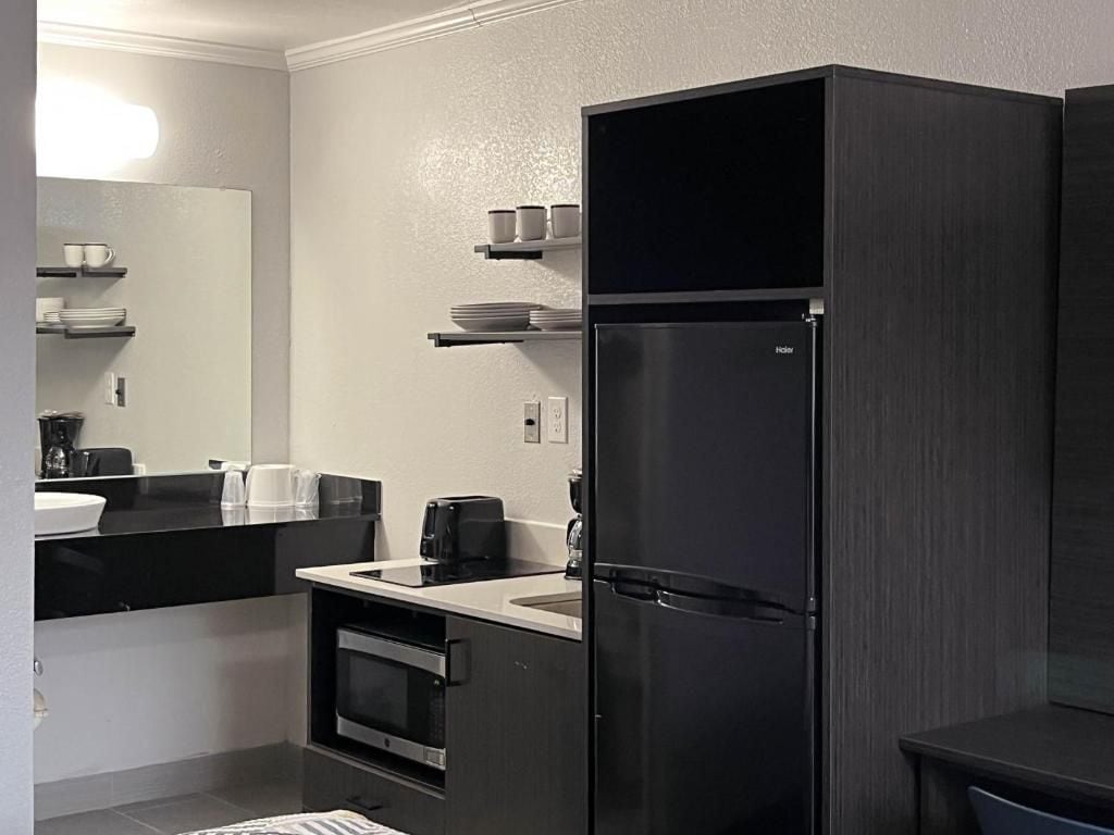 A modern kitchen with a black refrigerator, a stove, and a sink.