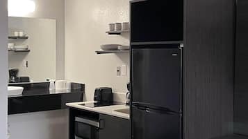 A modern kitchen with a black refrigerator, a stove, and a sink.